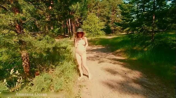 A nudist girl walks in forest near the beach among dressed people. (Emerald Ocean)